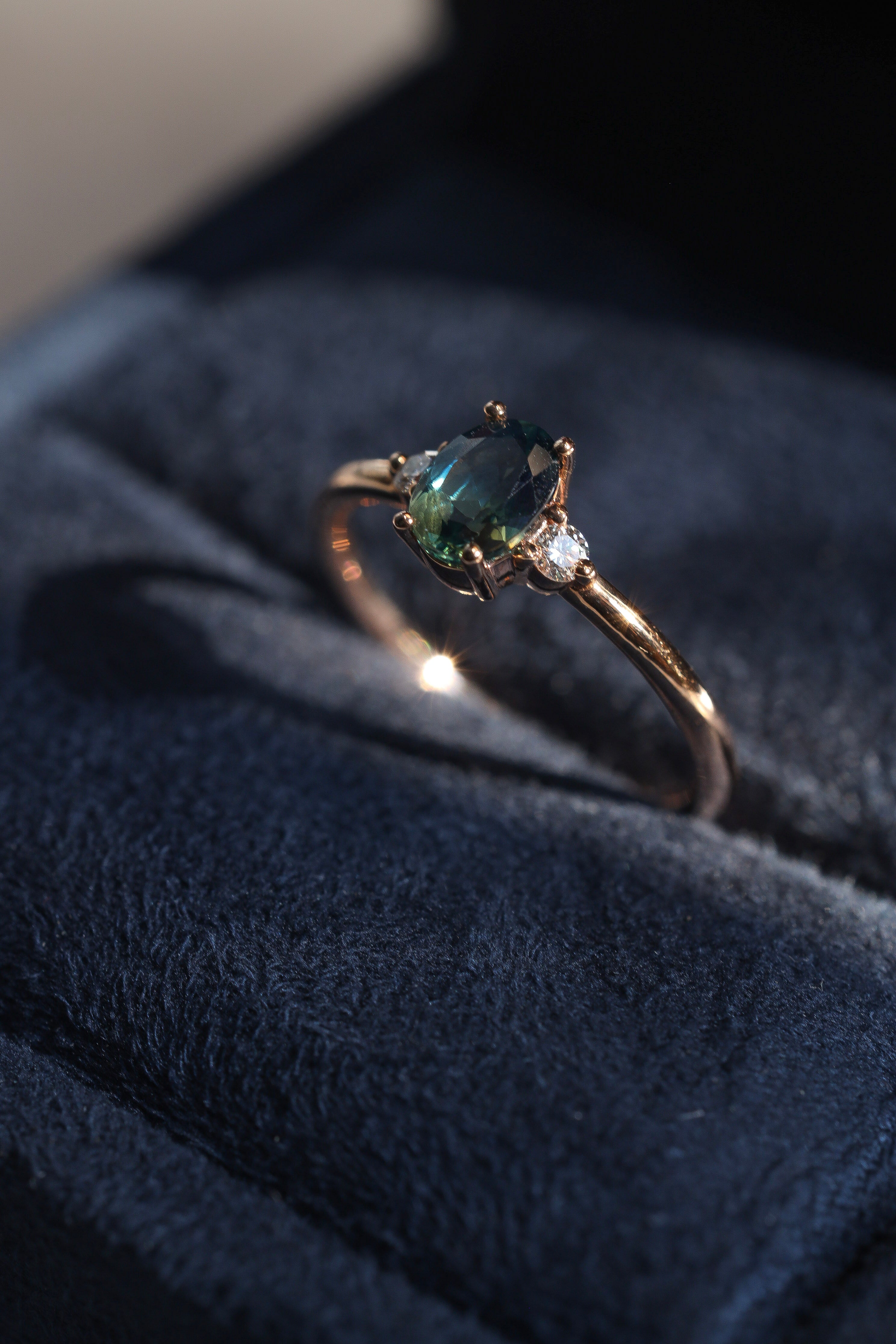 green sapphire ring with round diamonds set in rose gold 