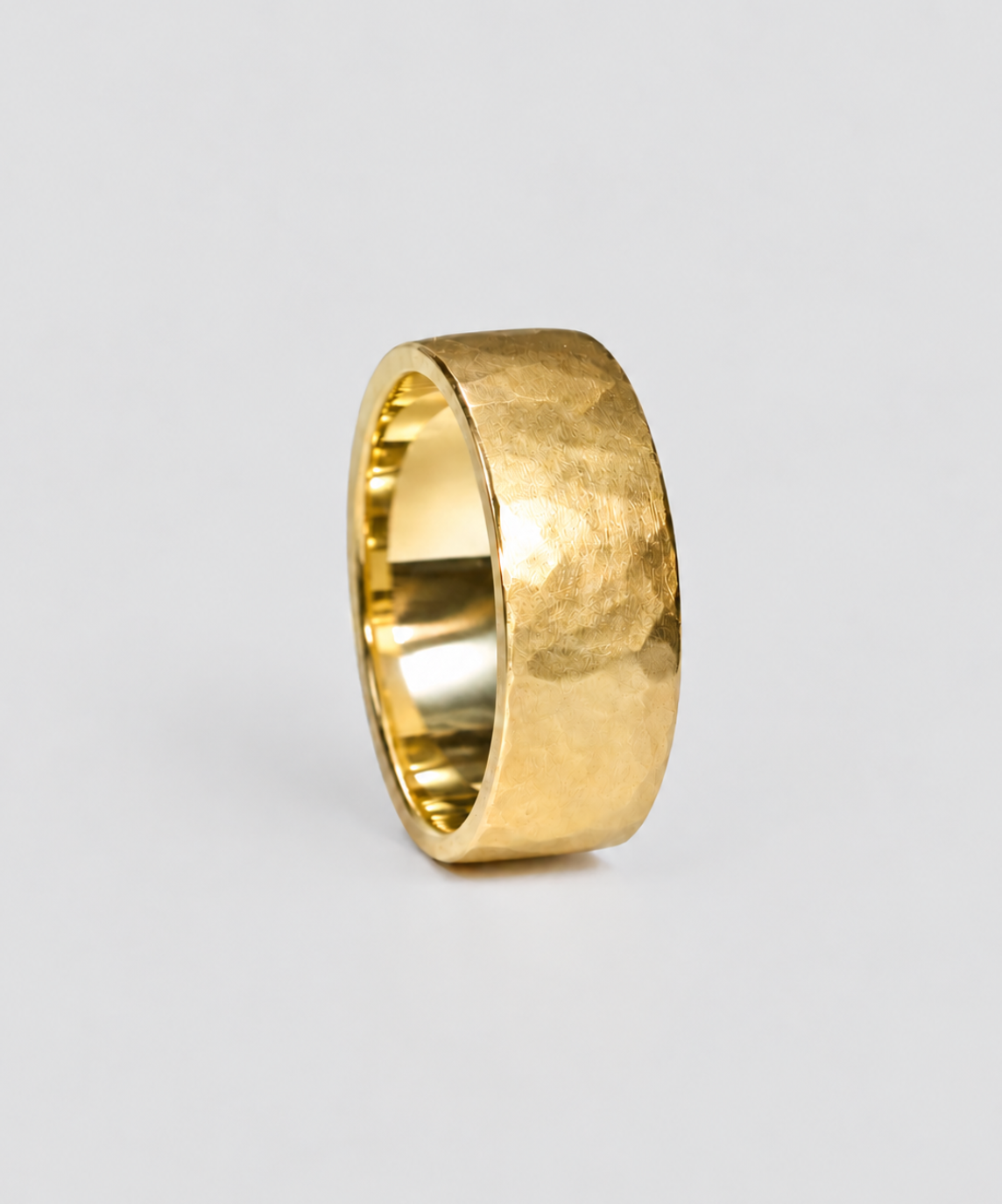 a yellow gold wide mens wedding band with hammered texture and brushed finish